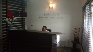 A reception desk with a sign reading "PEACOCK APARTMENTS AND SUITES". - Orchid Suite & Apartment (Abuja)