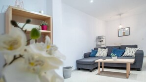 A modern living room with a grey sofa, wooden coffee table, and a small plant. - Apartamento El Patio de Cánovas (Cádiz)