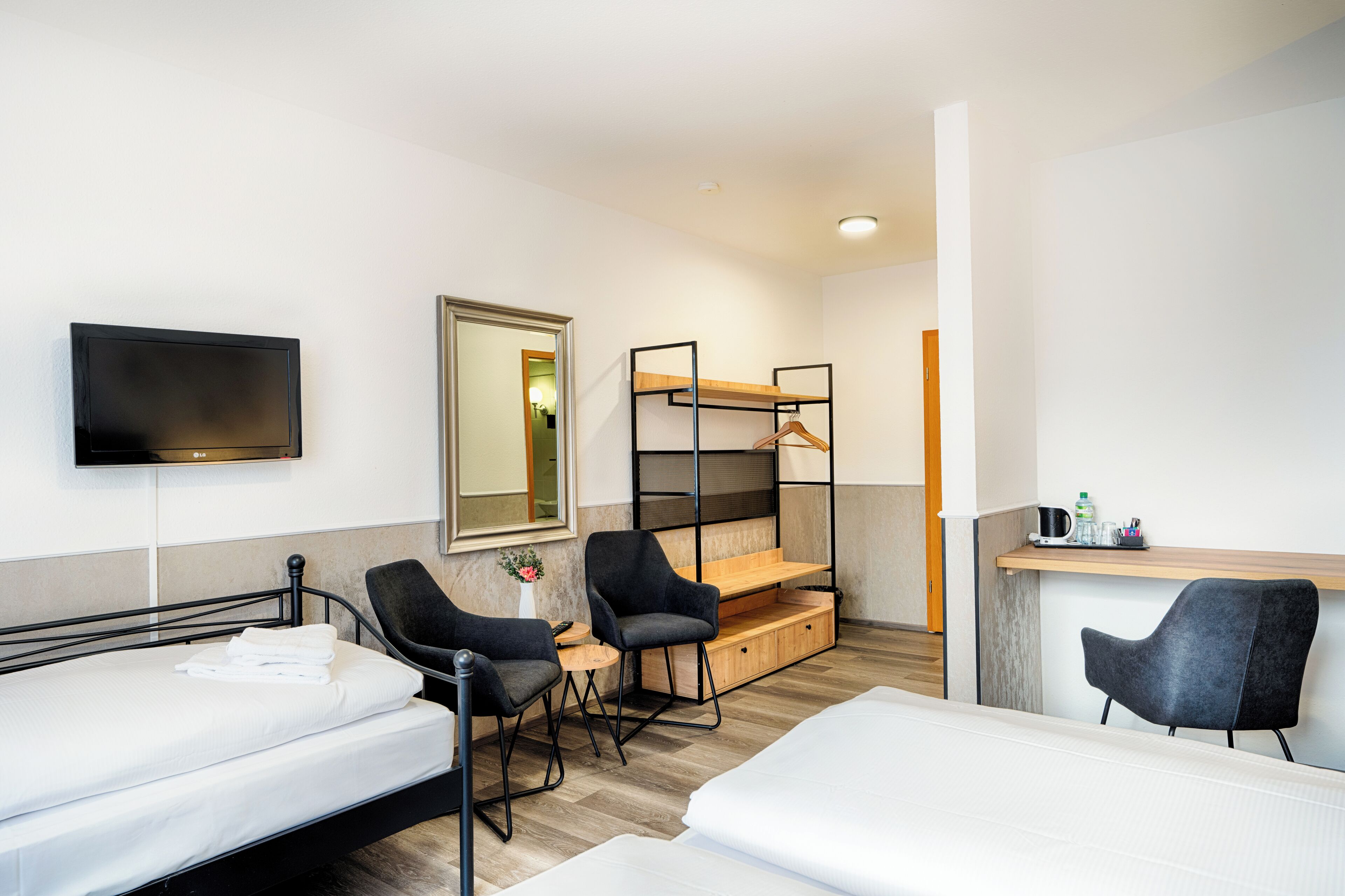 Ett hotellrum med en säng, två stolar, ett skrivbord, en tv och en våningssäng.