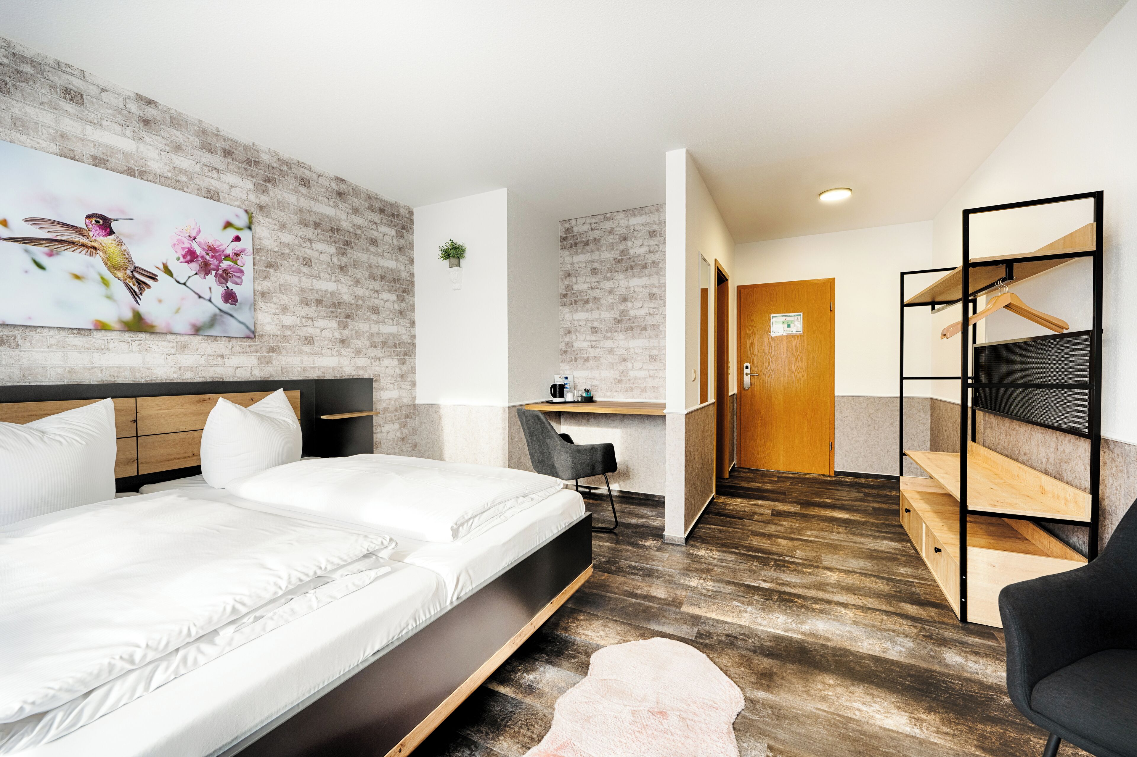 A modern hotel room with a large bed, a desk, and a seating area.