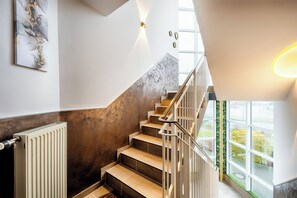 A modern staircase with a marble wall, a radiator, and a view of greenery outside. - Hotel Apfelblüte (Wendorf)