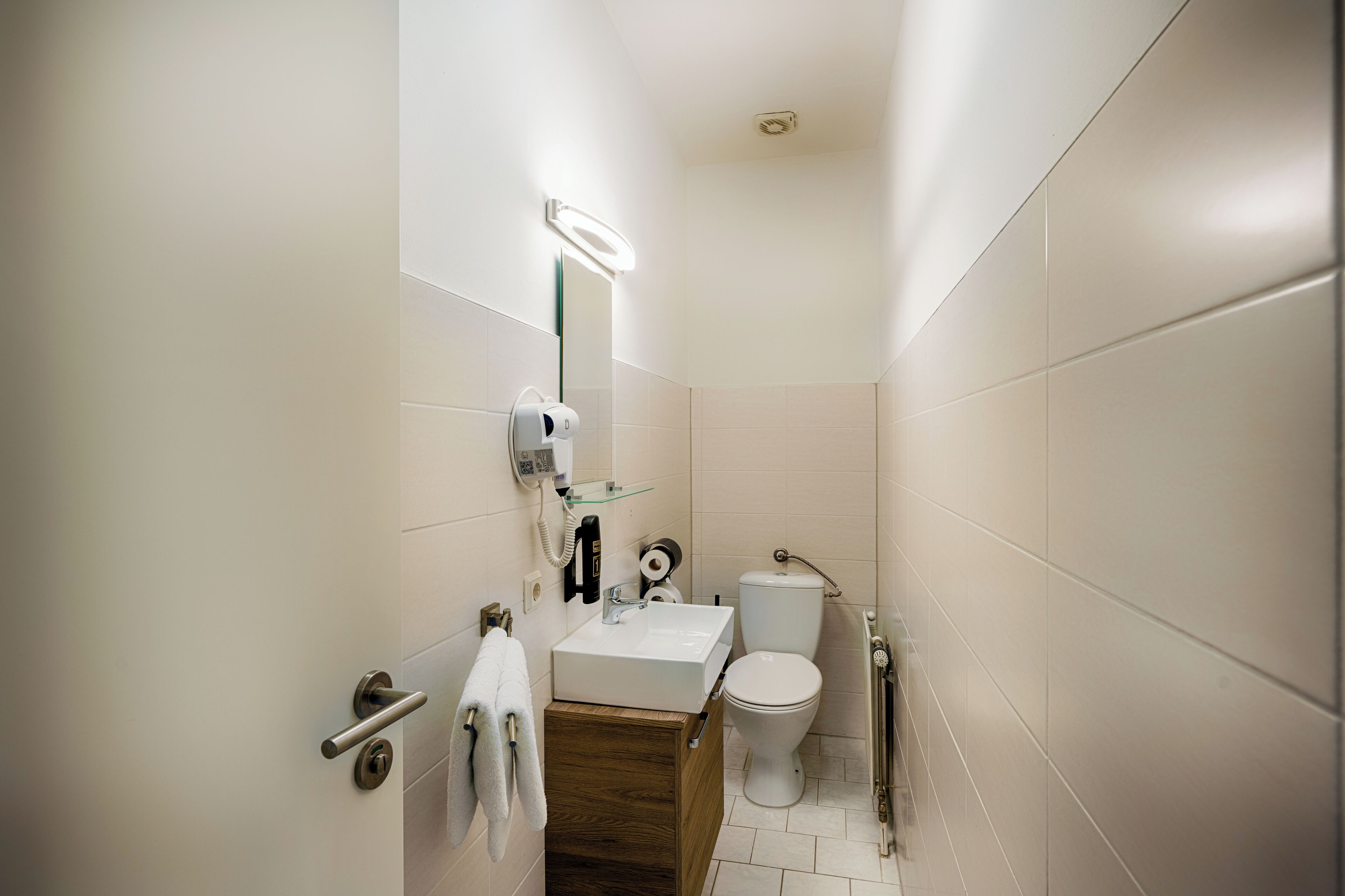 Une petite salle de bain avec un lavabo blanc, un miroir et des toilettes.