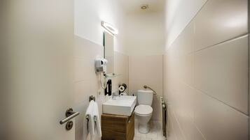 Une petite salle de bain avec un lavabo blanc, un miroir et des toilettes.