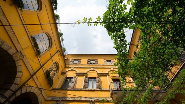A yellow building with arched windows and balconies, surrounded by greenery. - Casa Magnolia- Big apartment near the Arena (Verona)