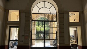 An arched entrance with a metal gate, a window with a spider web, and a door leading to a courtyard with bicycles. - Casa Magnolia- Big apartment near the Arena (Verona)