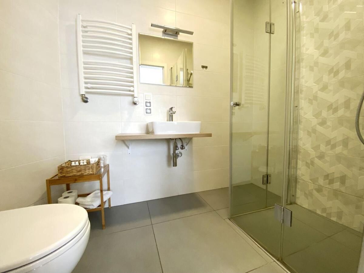 Een badkamer met toilet, wastafel met spiegel, douche en handdoekrek.