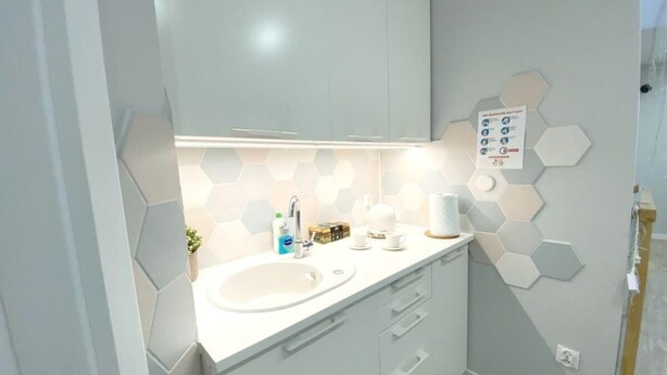 A modern bathroom with a white sink, a mirror, and a hexagonal tile backsplash. - Pensjonat Borek (Medyka)