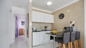 Una cocina moderna con armarios blancos, un microondas y un frutero sobre la encimera.
