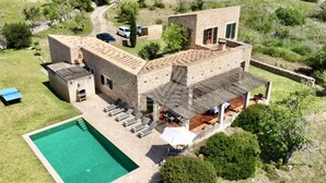 A modern villa with a swimming pool, outdoor seating, and a stone facade. - Mallorcan charm with countryside views and pool (Son Servera)