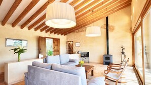 A modern living room with a sofa, a coffee table, and a wooden bench. There is a TV, a fireplace, and a large window. - Mallorcan charm with countryside views and pool (Son Servera)