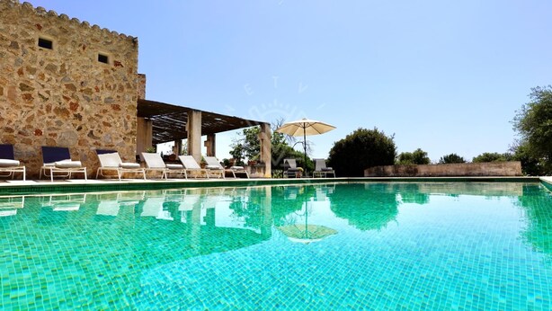 A clear blue pool with lounge chairs and umbrellas, a stone wall, and a pergola. - Mallorcan charm with countryside views and pool (Son Servera)