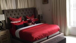 A bedroom with a large bed, a headboard, a nightstand, and a bench. - Perfect Havens at Platinum 5 (Lagos)