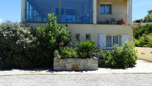 Ein zweistöckiges Gebäude mit großen Fenstern, einem Balkon und einem Steingarten mit Pflanzen.