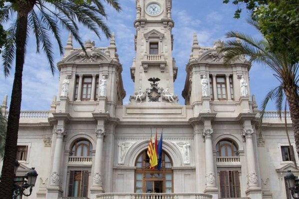 Un edificio storico con una torre dell'orologio, facciata simmetrica e bandiere.