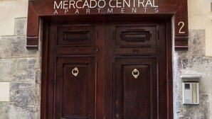A double wooden door with a brass handle, labeled "MERCADO CENTRAL APARTMENTS" above it.
