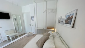 Une chambre moderne avec un grand lit, un banc, une armoire et un téléviseur à écran plat.