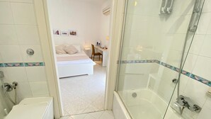 Une salle de bain moderne avec une douche à parois de verre, des toilettes et un lit dans la pièce adjacente.