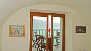 A room with a balcony, wooden furniture, and two framed artworks on the walls.