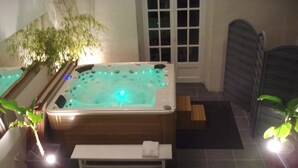 Un'area benessere con vasca idromassaggio, una panca e piante in vaso.