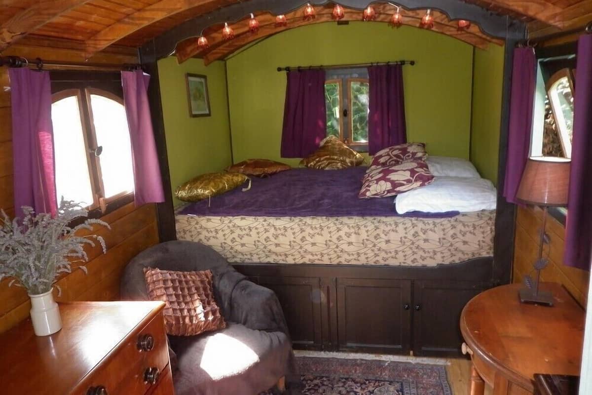 A cozy room with a bed, a chair, a dresser, and a small table.