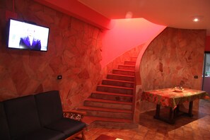 A room with a stone wall, a staircase, a sofa, and a table with a tablecloth. - Awsome Villa with large Private Pool, Garden & Terrace + Wifi & Bikes (Fontane Bianche)
