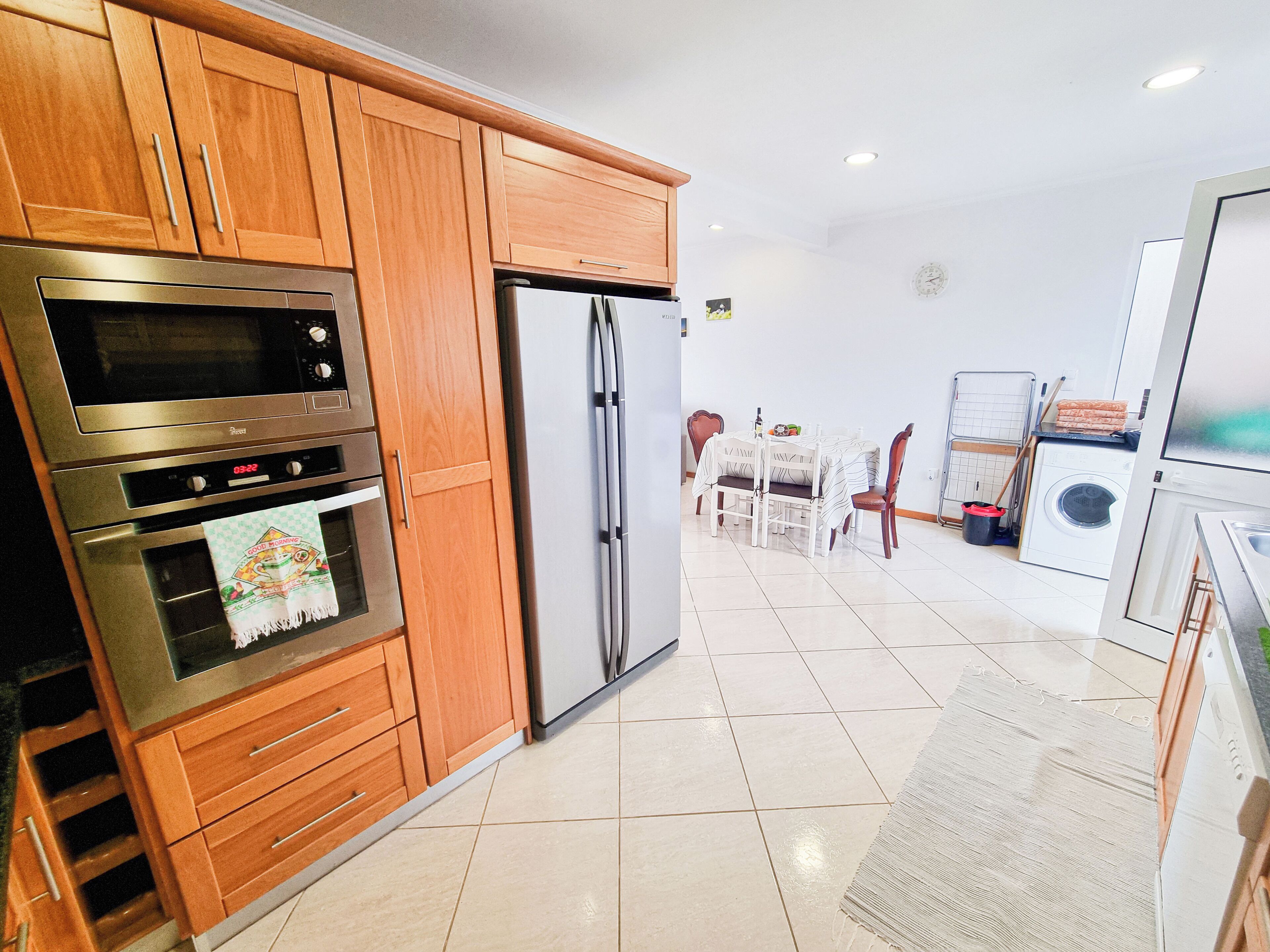A modern kitchen with wooden cabinets, stainless steel appliances, and a dining area with a table and chairs.