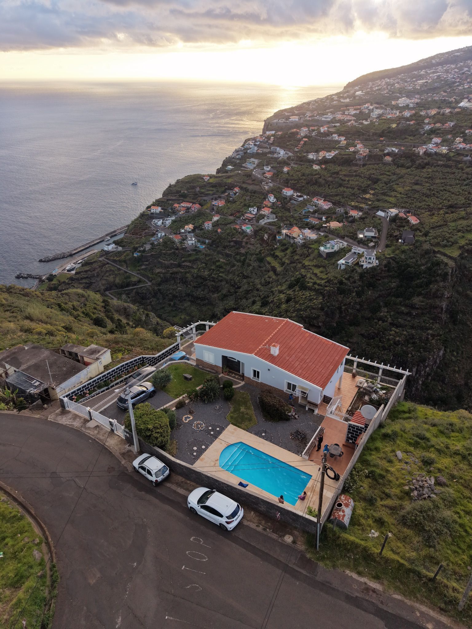 A coastal house with a swimming pool, surrounded by greenery and a view of the sea.