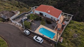 Ein Küstenhaus mit Swimmingpool, umgeben von viel Grün und Blick auf das Meer.