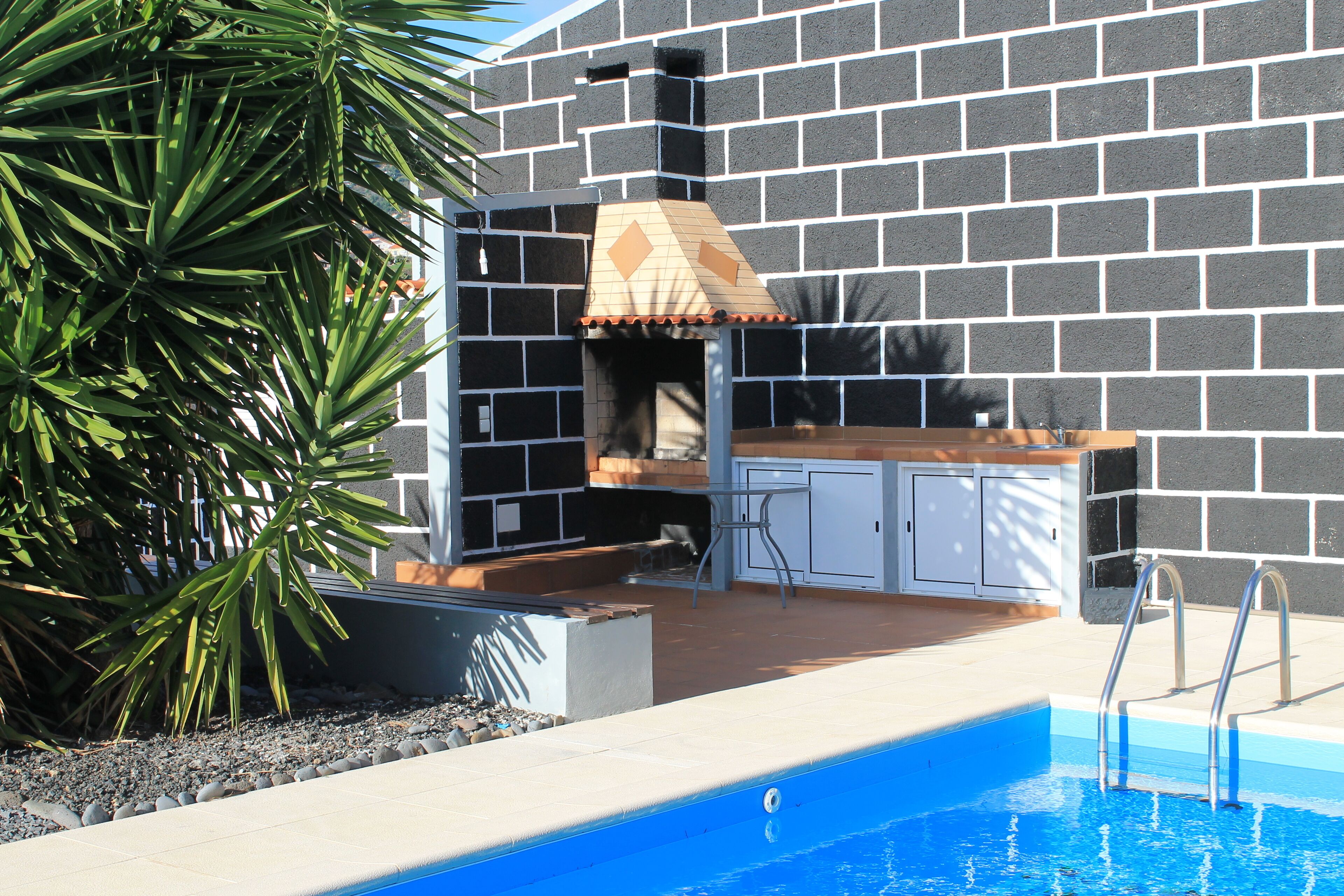 A poolside area with a barbecue grill, seating, and a pool.