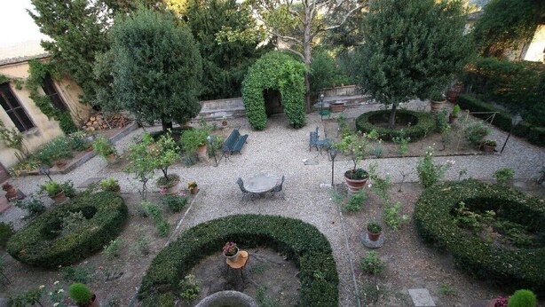 Un pati interior amb una zona d'estar central, envoltat de diverses jardineres i plantes en testos.