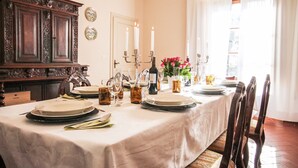 Taula de dinar preparada amb plats, gots i espelmes, juntament amb un armari de fusta i una finestra amb cortines.
