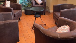 A living room with brown leather sofas, a round table, and a mural on the wall. - Auberge du Porche (Blaye)
