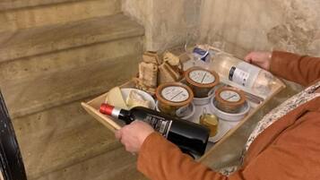 A person carrying a tray with a bottle, glasses, and food items.