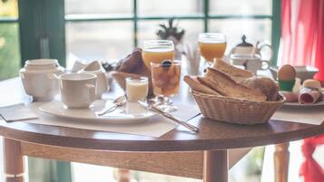 A breakfast table with various breakfast items, including bread, eggs, and beverages.