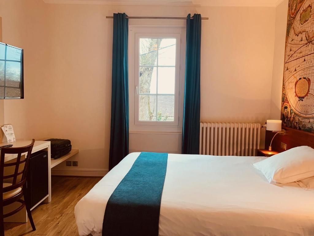 Une chambre d’hôtel avec un lit, un bureau, une chaise, un radiateur et une tapisserie au mur.
