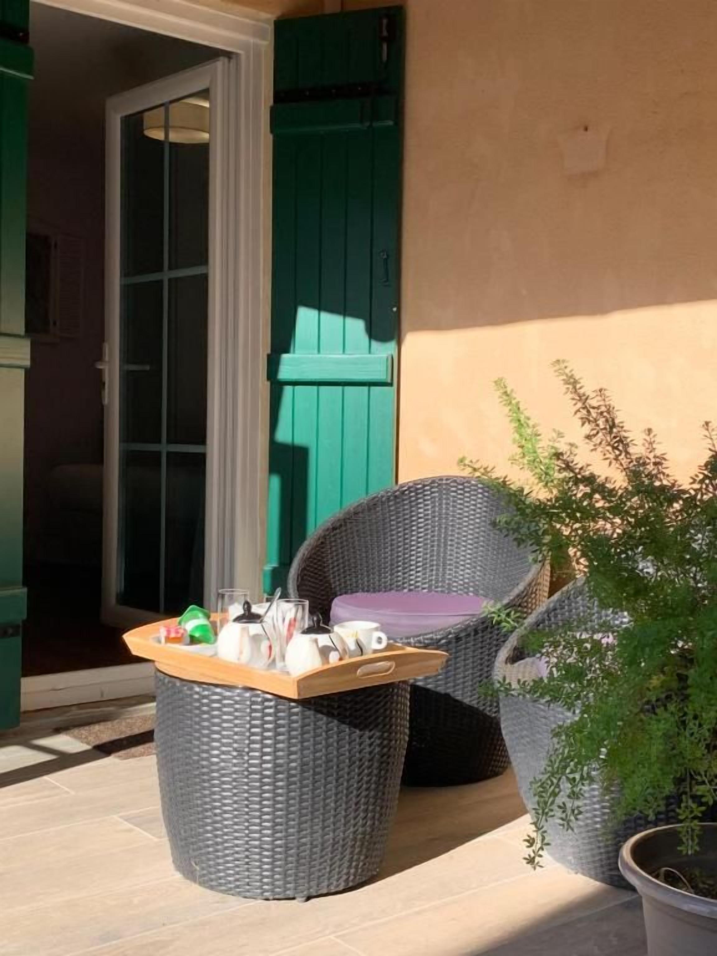 A wicker chair and a small table with a tray of items on a patio.