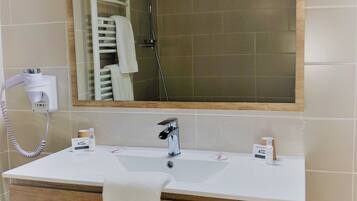 Een badkamer met een witte wastafel, een spiegel, een handdoek en een douche.