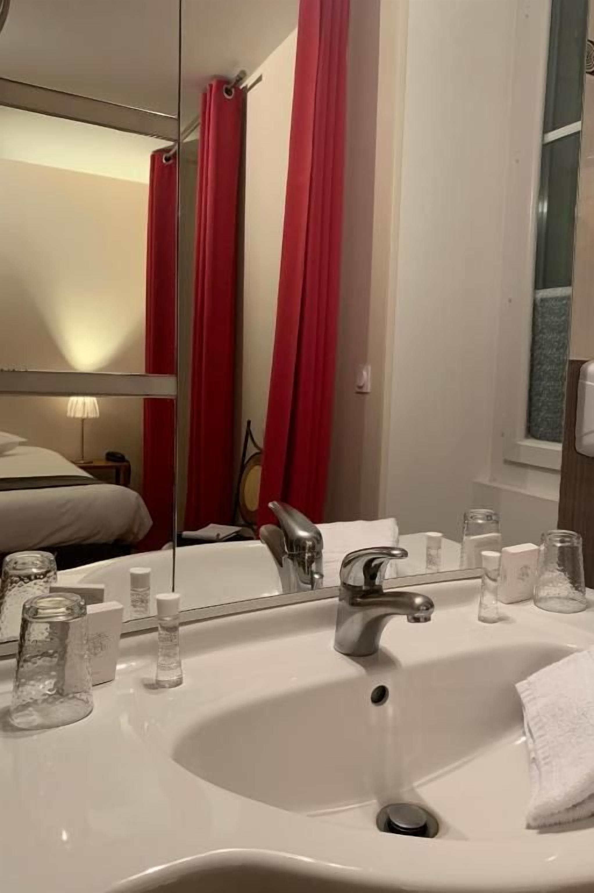 A bathroom with a white sink, a mirror, and red curtains.