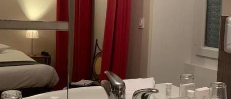 A bathroom with a white sink, a mirror, and red curtains.