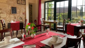 A dining area with tables set for two, featuring red tablecloths and white napkins. - Auberge du Porche (Blaye)
