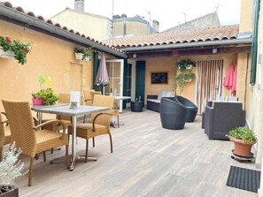 An outdoor patio area with wicker furniture, a table, and potted plants. - Auberge du Porche (Blaye)