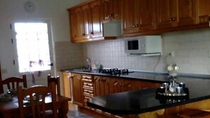 Eine Küche mit Holzausstattung, einer schwarzen Arbeitsplatte, einer Mikrowelle und einem Spülbecken.