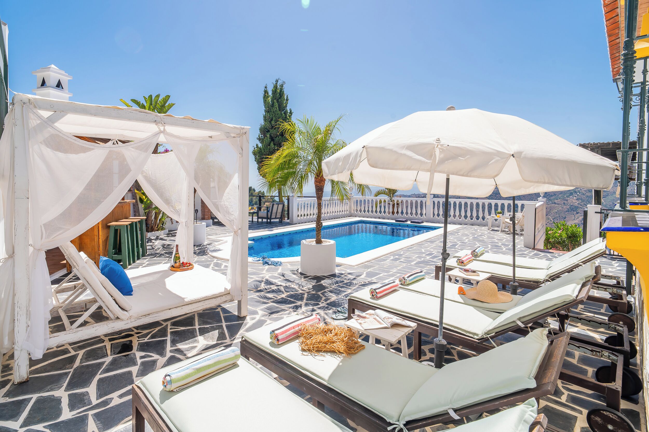 Un espace aménagé au bord de la piscine, avec des chaises longues, des parasols et une piscine.