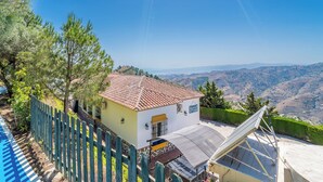 A house with a tiled roof, a solar panel, and a view of the hills.