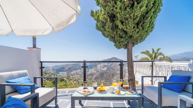 A terrace with a table set for breakfast, outdoor seating, and a view of the landscape.