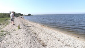 A pebbled beach with a person standing on the left. - Beautiful quiet 2 persons caravan on the Lauwersmeer (Anjum)