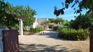 Ein Kiesweg führt zu einem Gebäude mit einer Pergola und Steinmauern.