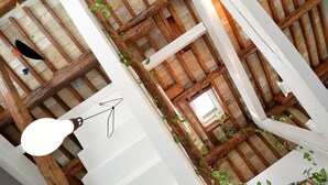 Una stanza con travi a vista in legno, soffitto bianco e lampadario.