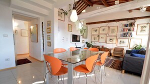 Un soggiorno moderno con tavolo da pranzo in vetro, sedie arancioni, un divano e una TV.