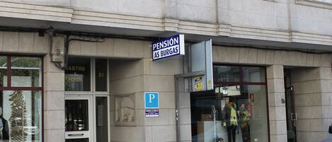 Un edificio con un cartel que dice 'Pension As Burgas' y un letrero de 'P' para estacionamiento.